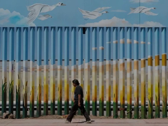 man walking in front of a border mural