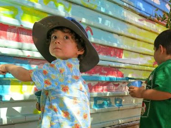two young kids painting a fence