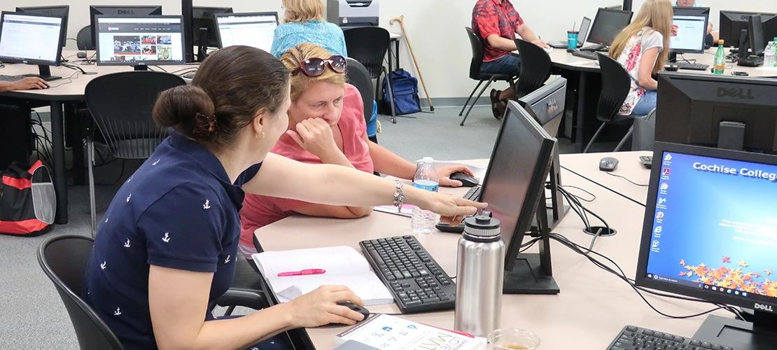 people in a room sitting in front of workstations