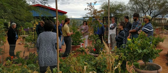 a group of people in a garden talking in a circle
